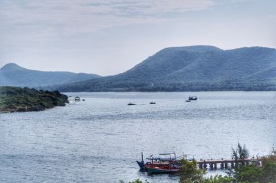 Boats sailing in sea against mountains