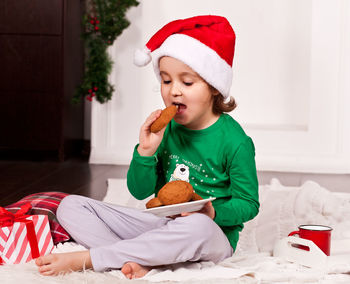 Portrait of cute girl playing with gift on bed at home