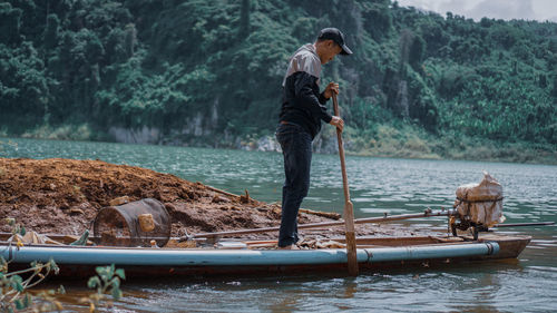 Man standing in river against trees