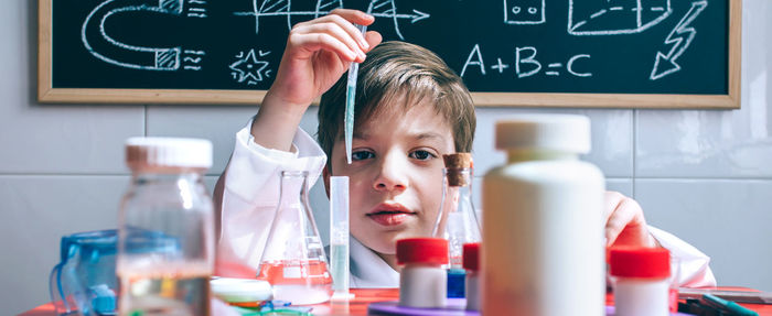 Portrait of cute boy examining chemical in classroom