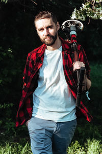 Midsection of man holding camera while standing on land