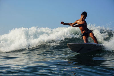 Man surfing in sea against sky