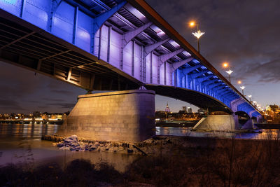 Low angle view of illuminated bridge over river at night