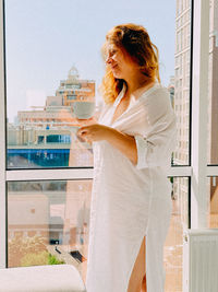 Side view of young woman standing against wall