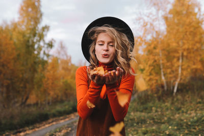 A pretty girl enjoys solitude drinks coffee walks in the autumn forest in nature in fall