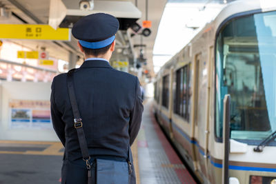 Rear view of man standing at railroad station