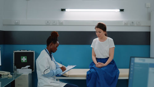 Female doctor using mobile phone while standing in hospital