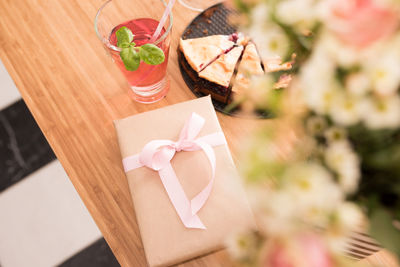 High angle view of flowers by gift with drink on table at home