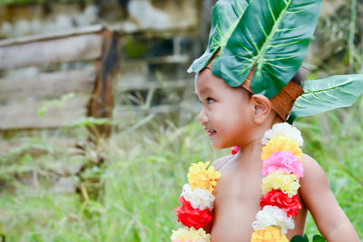 Cute boy looking up while standing against plants