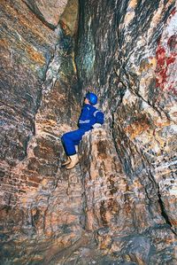 Man work underground in dark tunnel. staff in protective suit check sediments in rocky wall or cave