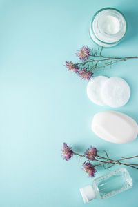 Cosmetic products and dry flowers on blue background. cream, lotion, soap, and cotton pads. 