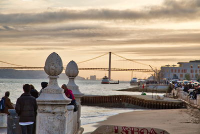 Rear view of people looking at bridge over sea