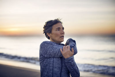 Woman exercising at beach against sky