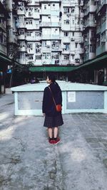 Full length rear view of young woman standing in city