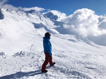 Rear view of man walking on snowcapped mountain