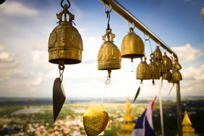 Golden bells hanging at temple against sky