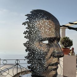 Close-up portrait of man sculpture by sea against sky