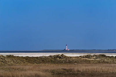 Scenic view of land and westerheversand lighthouse in remote