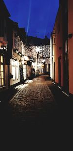 Empty alley amidst buildings at night