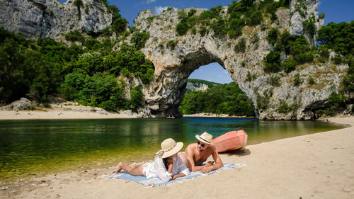 Rear view of woman relaxing on rock at beach