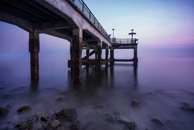 Pier over sea against sky during sunset