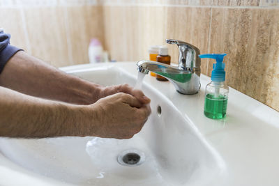 Midsection of man with faucet in bathroom