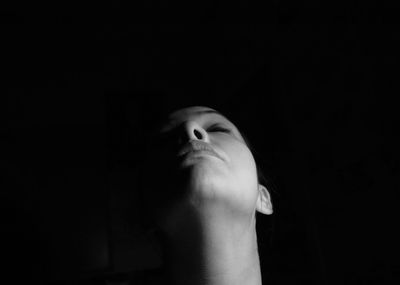 Close-up of woman with eyes closed in darkroom