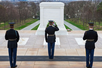 Rear view of army soldiers standing at monument