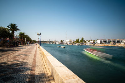 View of swimming pool by buildings against clear sky