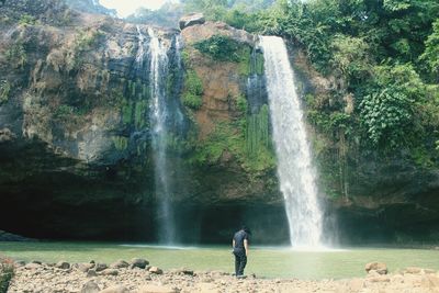 Man standing against waterfall