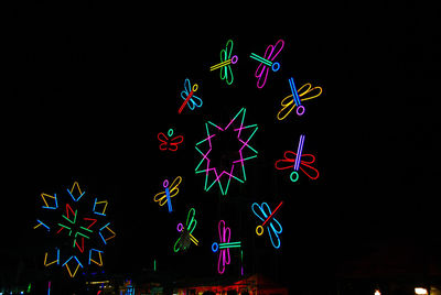 Low angle view of illuminated lighting equipment against black background