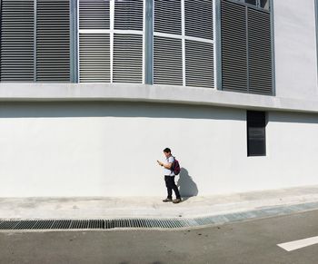 Man walking on footpath against building in city