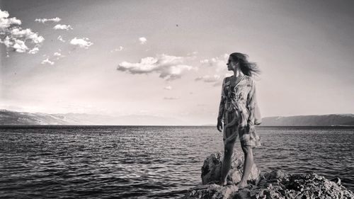 Woman standing by sea against sky