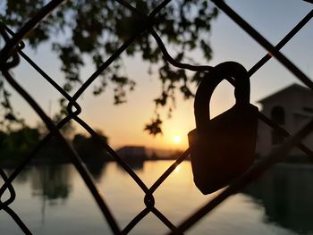 Close-up of silhouette chainlink fence against sky during sunset