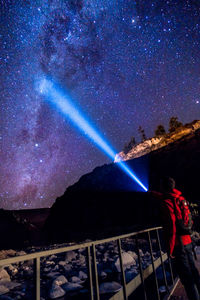 Man holding flashlight against star field