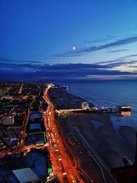High angle view of illuminated city by sea at night