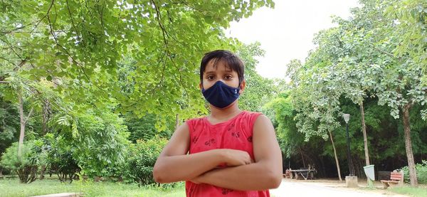 Portrait of boy standing against trees