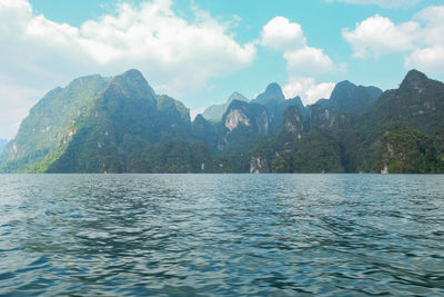 Scenic view of sea by mountain against sky