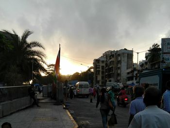 People on street against sky at sunset