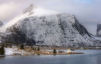 Scenic view of lake by snowcapped mountain against sky