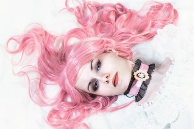 Portrait of young woman with pink petals against white background