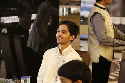 High angle view of happy teenage boy sitting at table in wedding ceremony