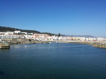 Town by sea against clear blue sky