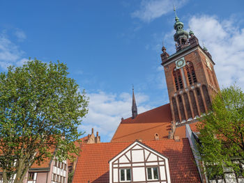 Low angle view of clock tower amidst buildings against sky