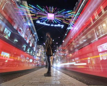 Blurred motion of woman standing on illuminated city at night