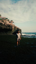 Rear view of woman walking on beach against sky