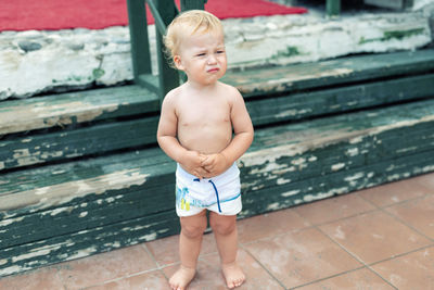 Full length of shirtless boy crying while standing outdoors