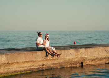 Dad and daughter in santa claus hats eat ice cream on the pier