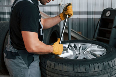 Working with broken wheel. man in uniform is working in the auto service.