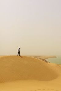 Man standing in desert against clear sky